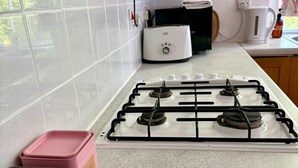 Keittiössä on kaasuliesi, valkoiset laatat, leivänpaahdin ja kaksi merkityllä etiketillä varustettua säiliötä.