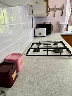 A kitchen with a gas stove, white tiles, a toaster, and two labeled containers. - Leafy Marchmont 2-Bed · Meadows · City Centre (Edinburgh)