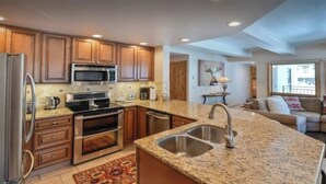 A kitchen with granite countertops, stainless steel appliances, wooden cabinets, and a built-in oven. - Ski Lodge Styled Plaza Condo 3 Bedroom Condo (Crested Butte)