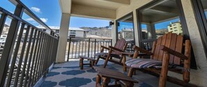 A balcony with wooden chairs and a table, a metal railing, and a view of buildings and hills. - Ski Lodge Styled Plaza Condo 3 Bedroom Condo (Crested Butte)