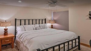 A bedroom with a bed, two bedside tables, a ceiling fan, and a window with blinds. - Ski Lodge Styled Plaza Condo 3 Bedroom Condo (Crested Butte)