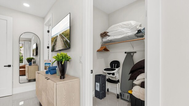 Ett kompakt hotellrum med en säng, ett sängbord, en stol, ett litet skrivbord, en spegel och en tv.