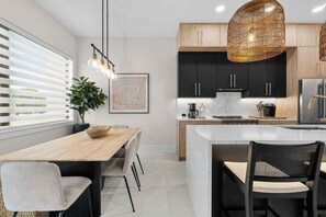 A modern kitchen with a central island, wooden cabinets, and a hanging light fixture. - Papaya Place 2 Bedroom Townhouse (Sarasota)