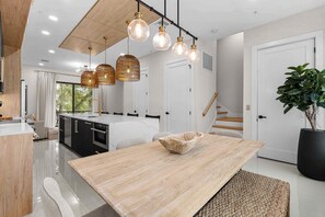 A modern kitchen with a central island, pendant lights, and a staircase leading to an upper level. - Papaya Place 2 Bedroom Townhouse (Sarasota)