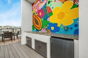 An outdoor kitchen area with a colorful mural, a stainless steel sink, and a wooden deck. - Papaya Place 2 Bedroom Townhouse (Sarasota)
