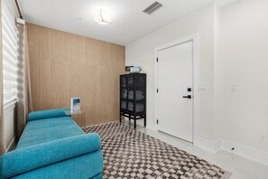 A room with a checkered floor, a door, a cabinet, and a blue sofa. - Papaya Place 2 Bedroom Townhouse (Sarasota)