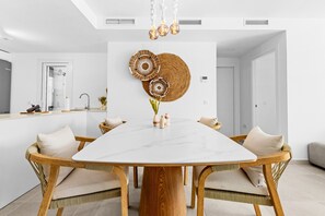 A modern dining area with a marble table, wicker chairs, and decorative wall art. - 13 - Modern 2BR near Cala de Mijas (La Cala de Mijas)