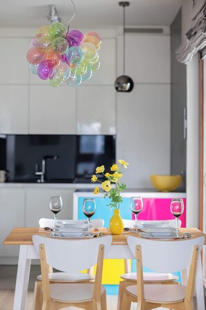 Ein Essbereich mit einem Tisch für zwei Personen, Stühlen, einer Vase mit gelben Blumen und einer bunten Ballondekoration.
