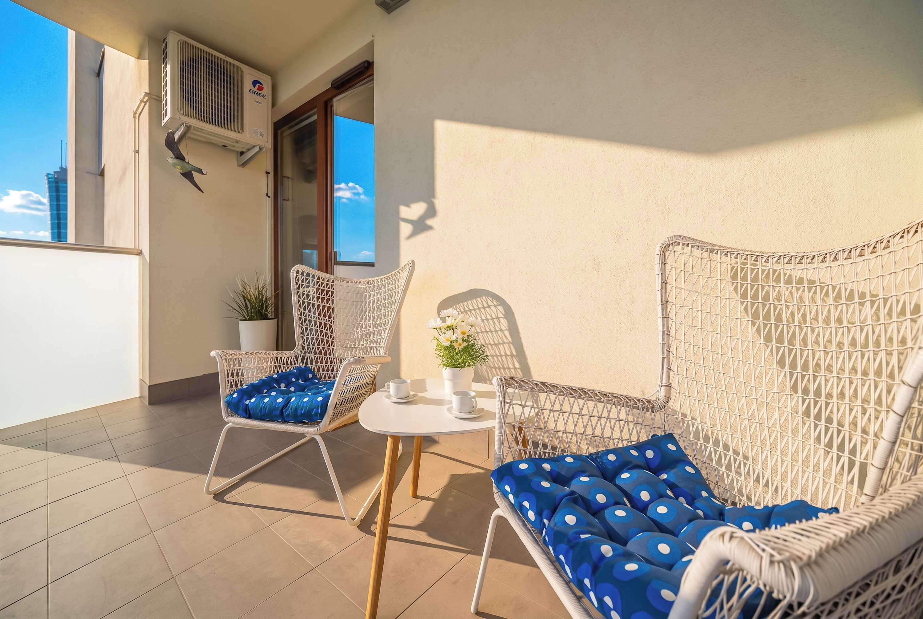 A balcony with wicker furniture, a small table, and a potted plant.