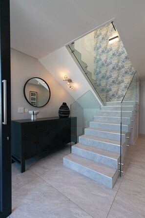 A modern staircase with glass railings and a decorative wall. - Miles End @ Pezula (Knysna)