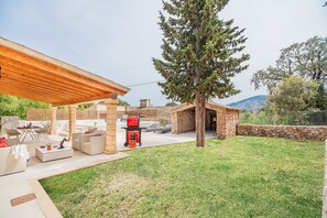 Eine Außenpatio-Terrasse mit Grill, Sitzgelegenheit und Steinkonstruktion.