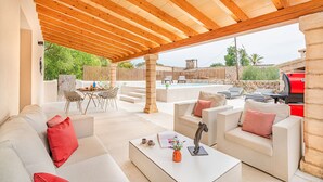 An outdoor patio area with a wooden ceiling, stone columns, a pool, and outdoor furniture. - Cosy 2-bed Villa With Pool, Pollenca (Pollença)