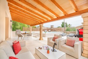 Eine Außenpatio-Terrasse mit Holzboden, Stein Säulen, einem Pool und Gartenmöbeln.