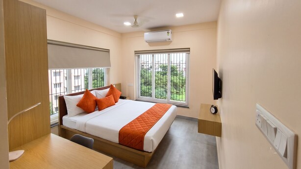 Une chambre d’hôtel équipée d’un lit, d’un bureau, d’une chaise, d’une télévision et d’une fenêtre donnant sur un paysage verdoyant.