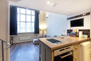 Eine moderne Küche mit Einbauherd, Flachbildfernseher und einem Fenster mit Vorhängen.