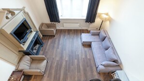 A living room with a fireplace, sofa, and a television. - One Bedroom Duplex in Paddington (London)