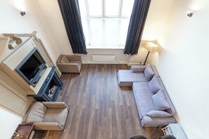 Ein Wohnzimmer mit Kamin, Sofa und Fernseher.