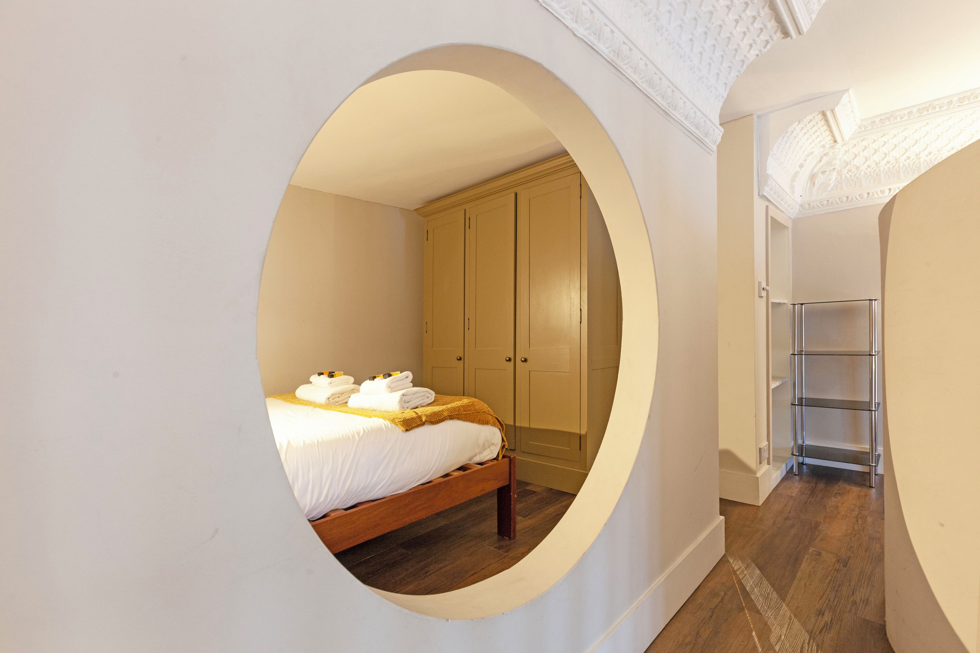 A bedroom with a bed, a wardrobe, and a circular window.