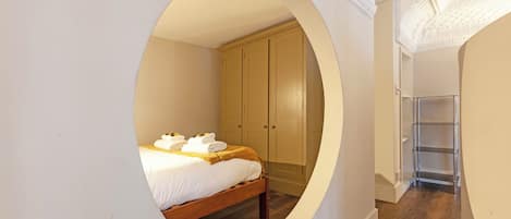 A bedroom with a bed, a wardrobe, and a circular window.