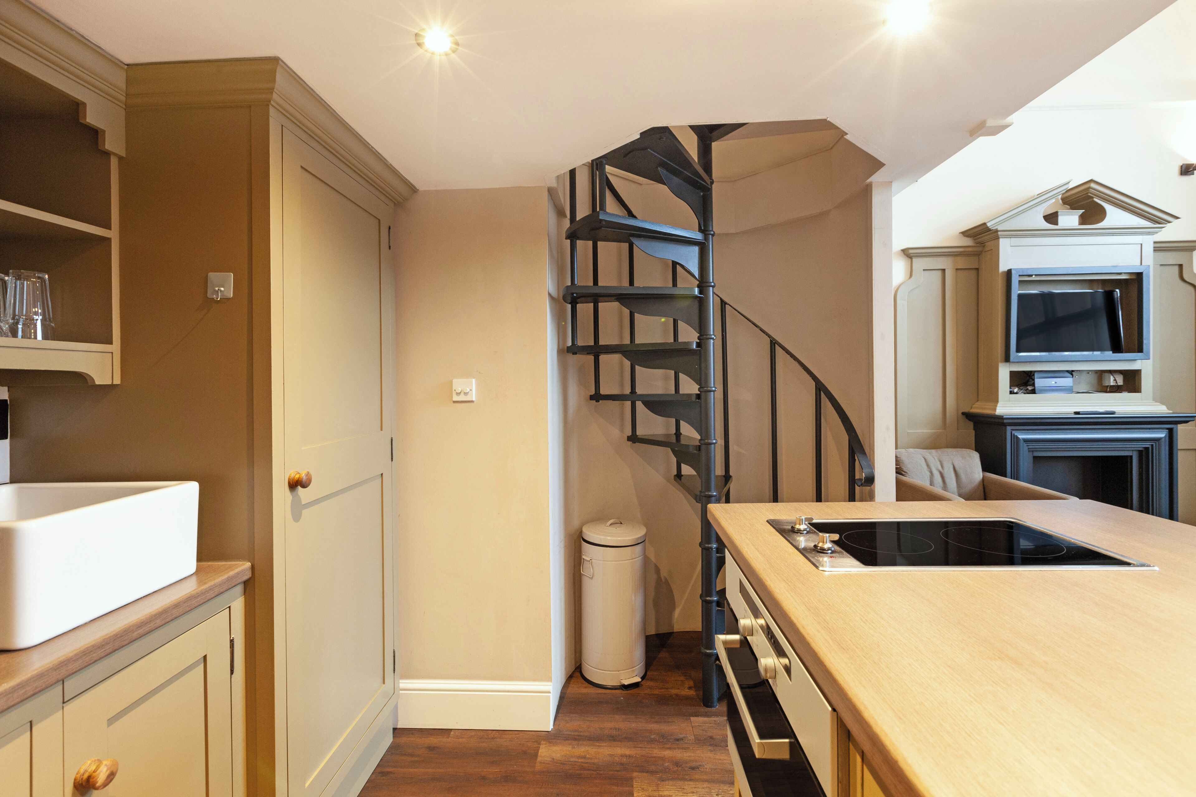 A kitchen with a wooden countertop, a built-in oven, and a spiral staircase.