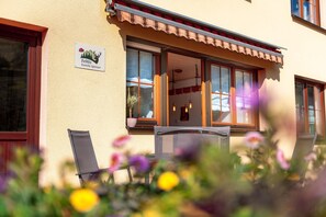 Ein Gebäude mit einem Schild, auf dem 'FeWo Familie Spinner' steht, und einem Fenster mit Blick ins Innere.