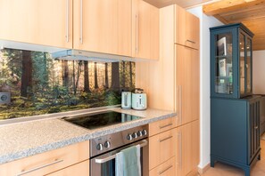 Eine moderne Küche mit Holzschränken, einem Backofen, einem Kochfeld und einer Mikrowelle.