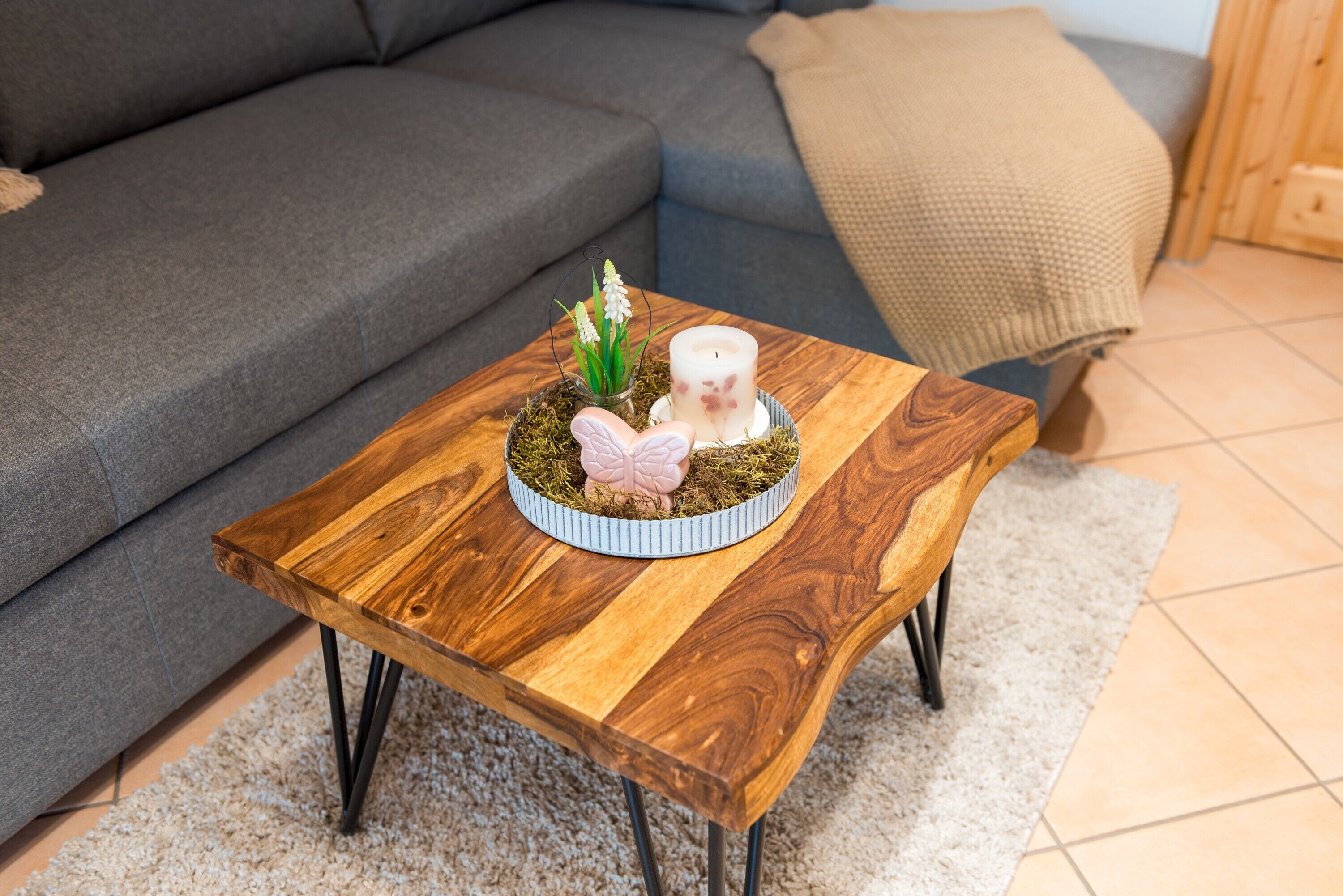 A wooden coffee table with a glass top, a small plant, and a decorative item on a rug.