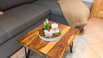 A wooden coffee table with a glass top, a small plant, and a decorative item on a rug.