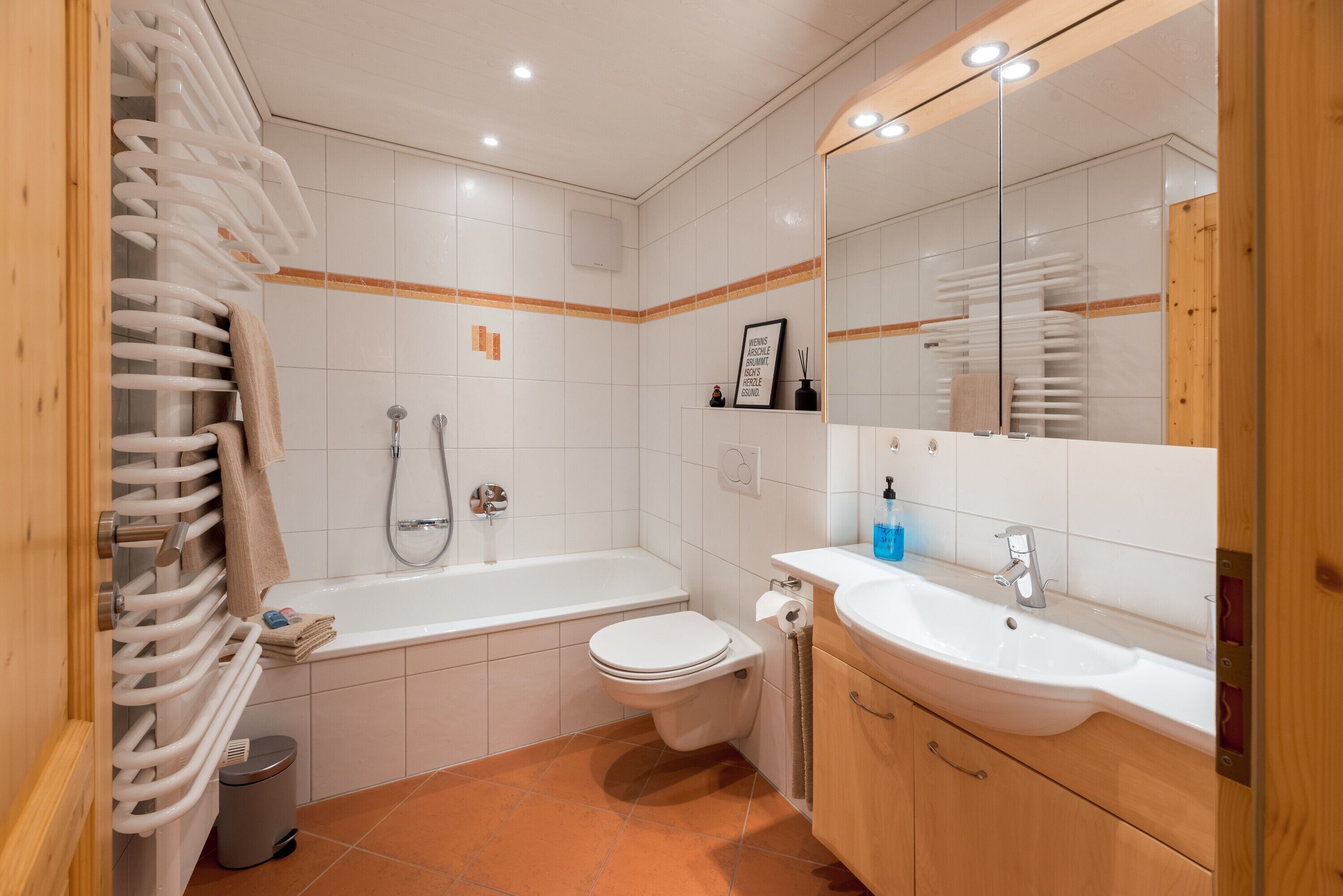 Een badkamer met bad, toilet, wastafel en handdoekrek.