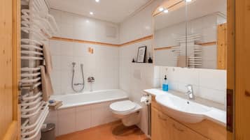Een badkamer met bad, toilet, wastafel en handdoekrek.