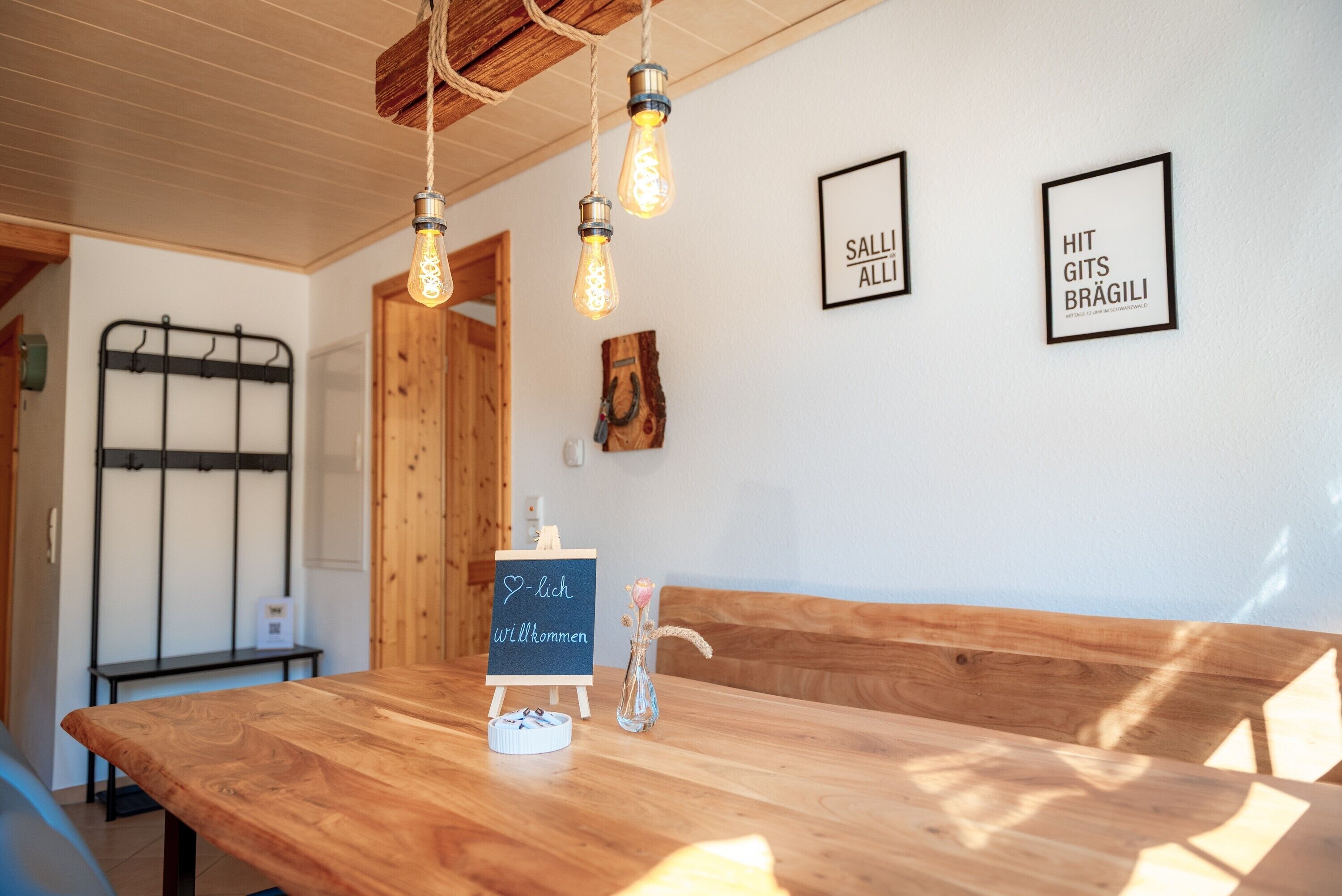 A wooden bench with a chalkboard sign, a metal rack, and framed text on the wall.