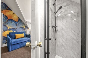 A modern bathroom with a glass shower enclosure and a marble wall.