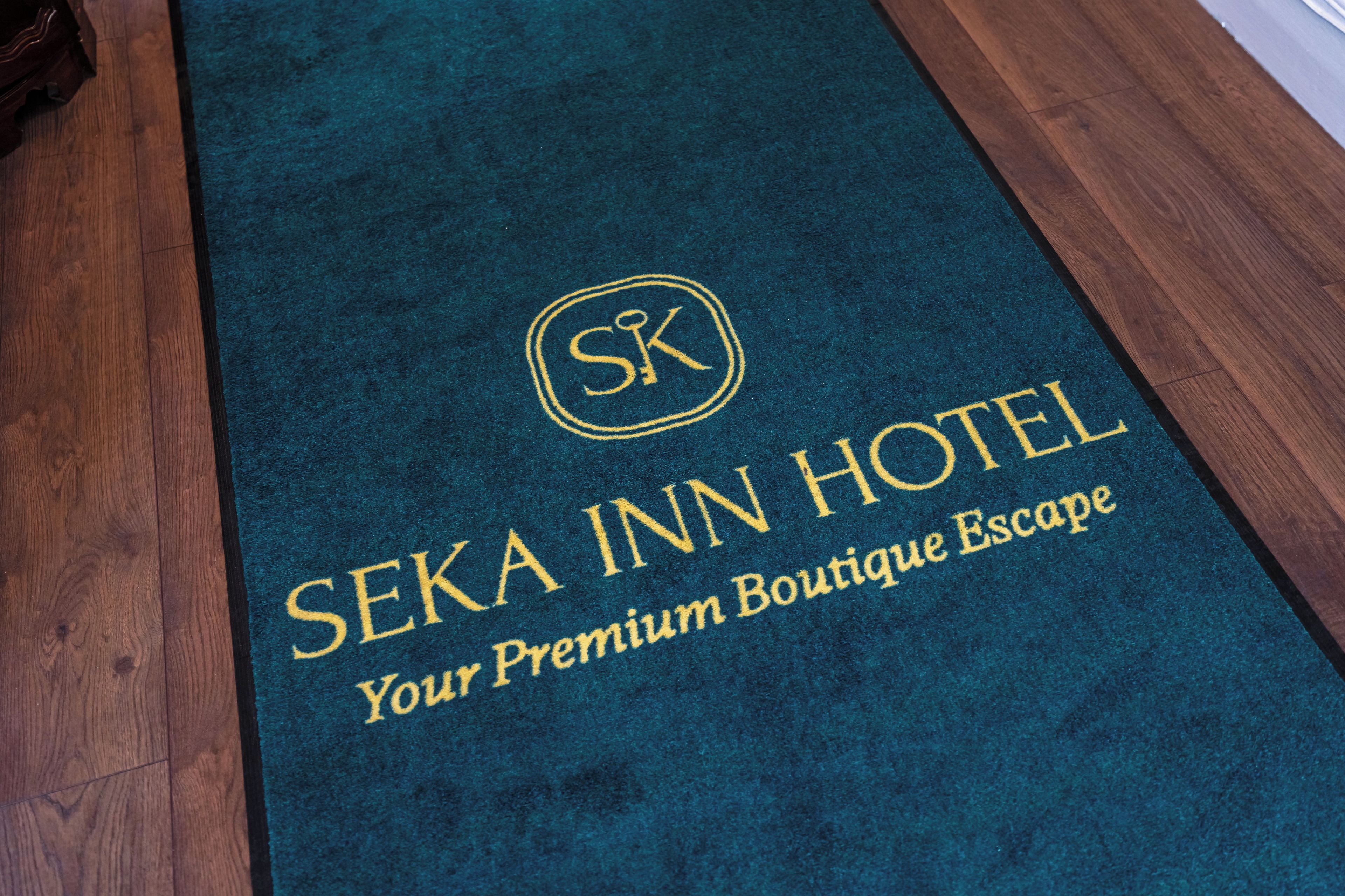 Ein dunkelblauer Teppich mit goldener Schrift, auf dem 'SEKA INN HOTEL' und 'Your Premium Boutique Escape' steht.