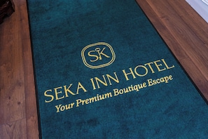 A dark blue carpet with gold lettering that reads 'SEKA INN HOTEL' and 'Your Premium Boutique Escape.' - Seka Inn Hotel (Crowthorne)