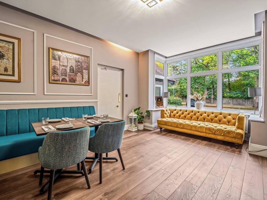 A dining area with a table set for four, a teal sofa, and a yellow sofa.