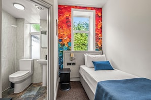 A compact room with a toilet, sink, and a bed with a blue pillow. - Seka Inn Hotel (Crowthorne)