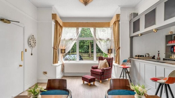 Ein Essbereich mit einem Holztisch, Stühlen und einem Fenster mit Vorhängen.