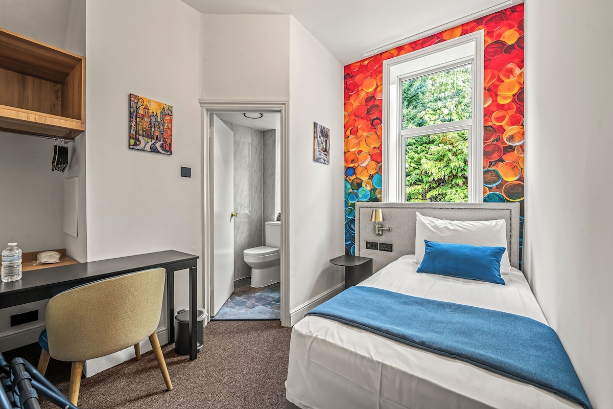 Habitación de hotel con cama, escritorio, silla, baño y ventana con vistas.