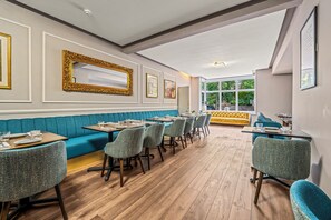 A restaurant interior with a long counter, blue upholstered booths, and a wooden floor.