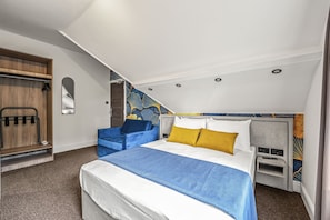 Una habitación de hotel moderna con cama, zona de estar y armario.