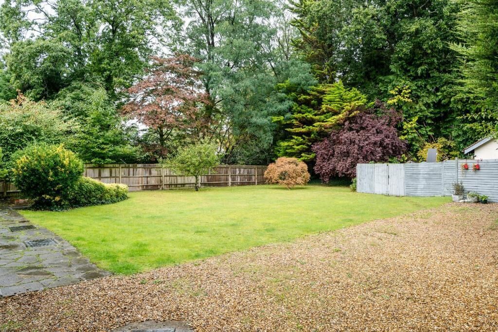 Un jardin avec un chemin de pierres, une pelouse et divers arbres et arbustes.