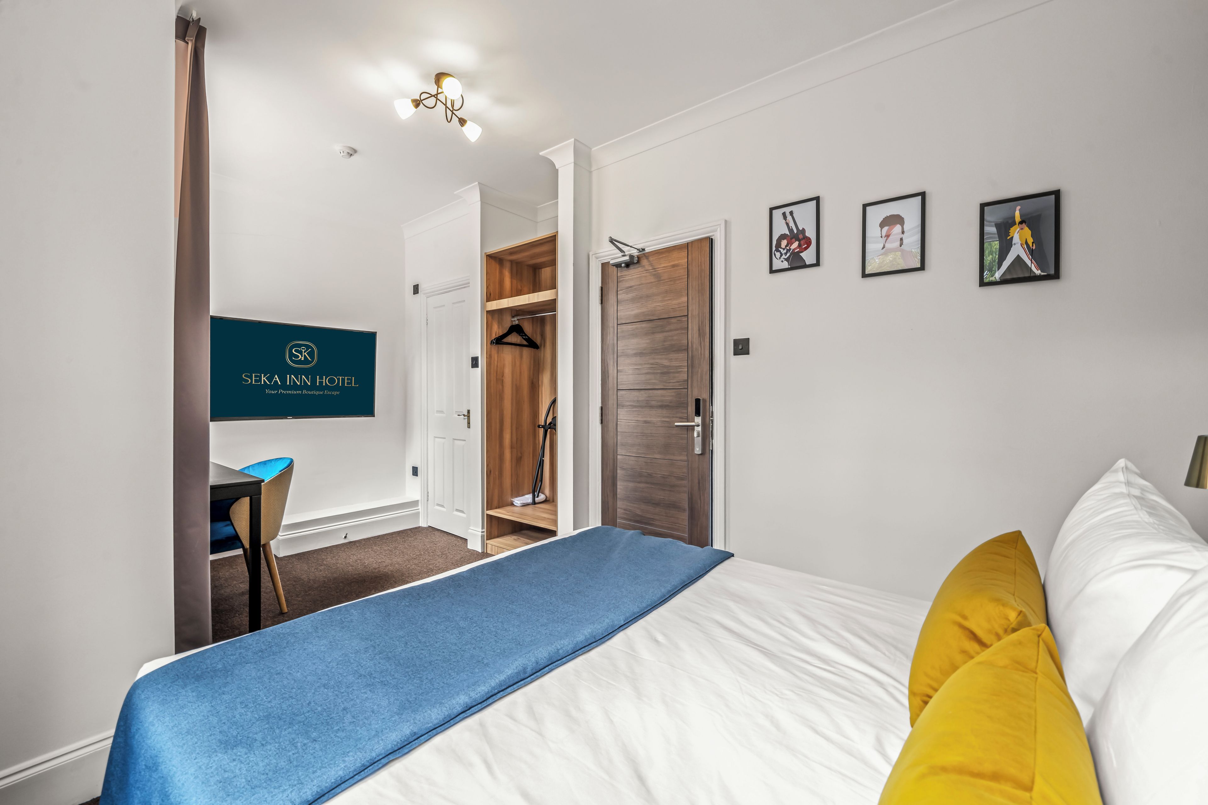 A hotel room with a bed, a desk, a wardrobe, and a shower area.