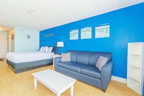 A room with a bed, a sofa, a coffee table, and a wall with three framed pictures. - Sea Mist 51012 Ocean View Escape (Myrtle Beach)
