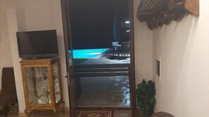An open doorway leading to a pool area with a television on the left. - A fully equipped, comfortable, and cozy studio apartment with a pool (Specchia)
