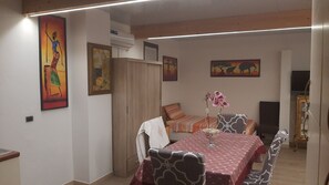 Ein Essbereich mit Tisch für vier Personen, einer Couch und einer dekorativen Orchidee.