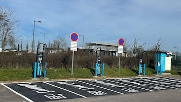 Un espace de stationnement équipé de bornes de recharge pour véhicules électriques, avec un bâtiment en arrière-plan.