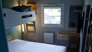 Pieni huone, jossa on kerrossängyt, pieni ikkuna, työpöytä ja tuoli.