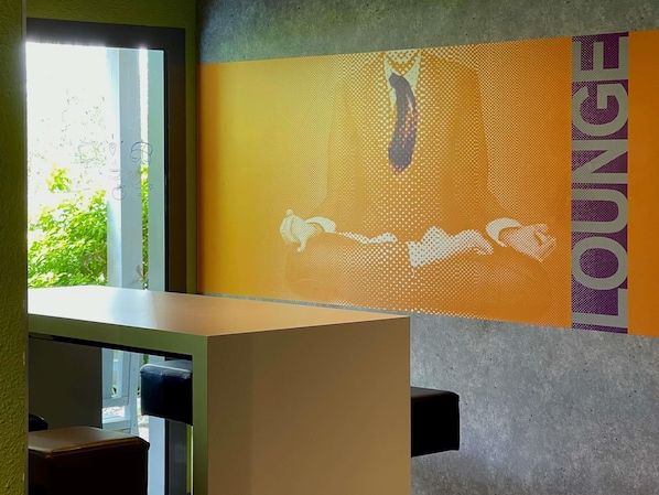 Una habitación con ventanal, pared con diseño gráfico y vista parcial de una cama.