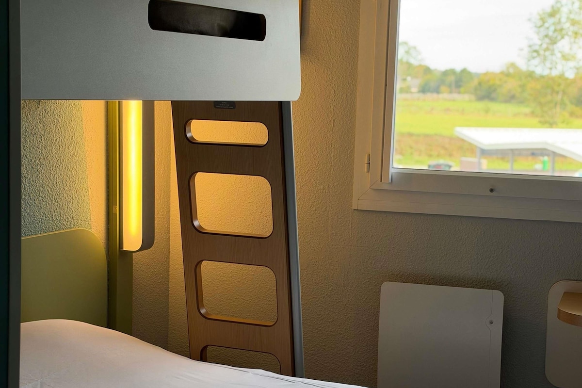 Un compartimento de tren con una cama, una ventana y una lámpara fijada a la pared.