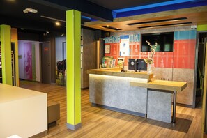 Zona de recepción con mostrador, techo de madera y pared con quiosco de registro.